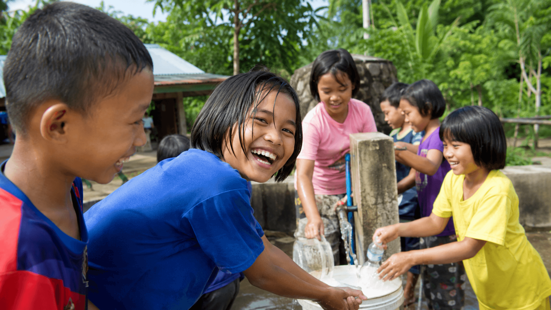 Thai children collecting and drinking clean water at community facility